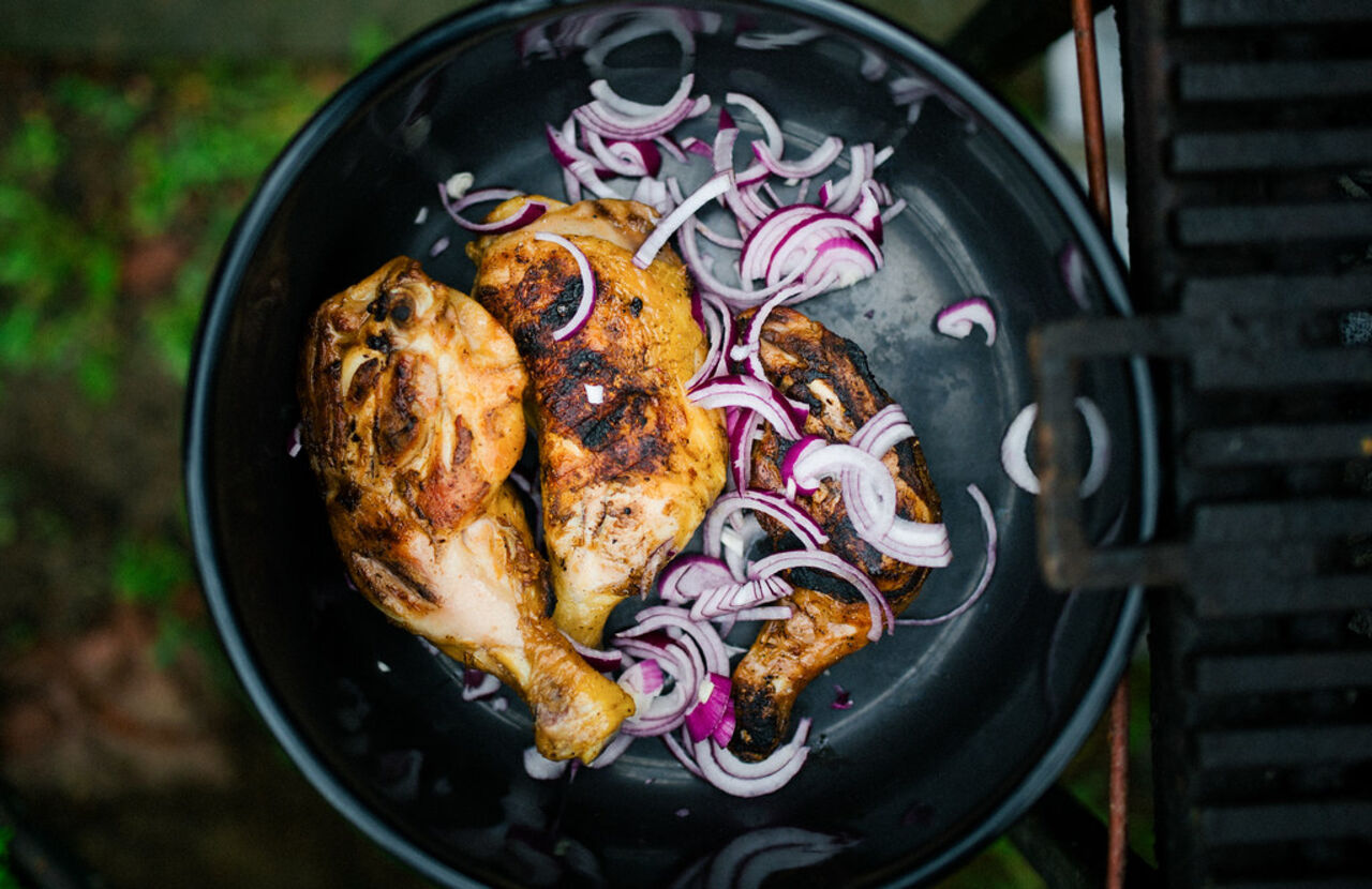 Fertig gegrillte Hähnchen-Drumsticks mit roten Zwiebeln in einer Schüssel